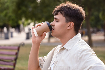 Obraz premium Handsome young man drinking delicious latte outdoors