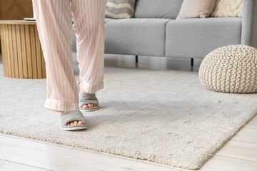 Woman in slippers walking on soft carpet at home, closeup