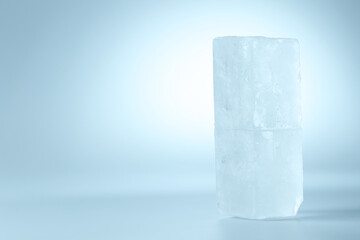 Blocks of clear ice on light blue background, space for text