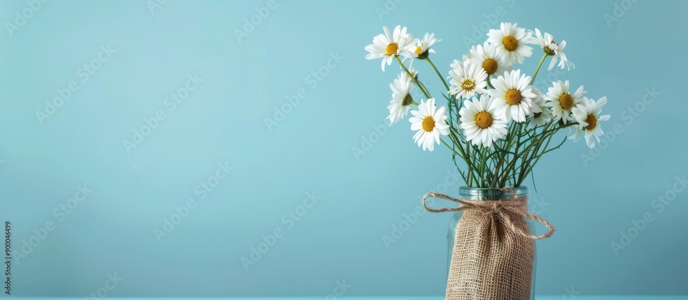 Leinwandbilder White daisy bouquet in a jar with a sack on a blue background perfect for adding a rustic touch to your project or design with copy space image