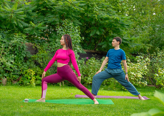 couple meditating doing yoga in nature.man and woman doing yoga exercises meditating on green grass