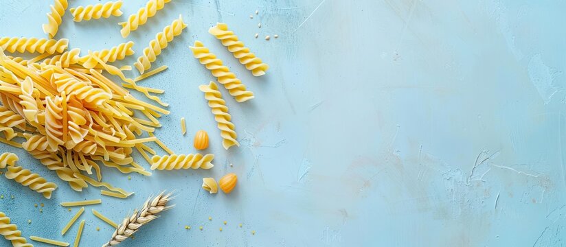 Trofie pasta uncooked on a light blue backdrop top down view with copy space image
