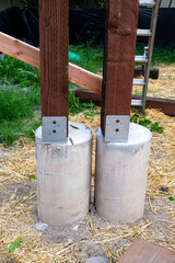 New house construction in residential neighborhood, closeup job site detail, round foundation cement pouring form with metal bracket and wood 4x4 beam installed  © knelson20
