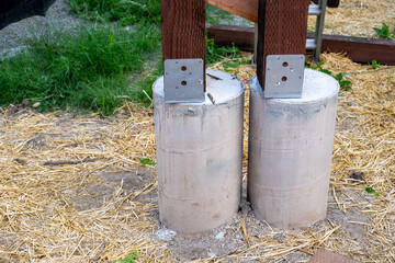 New house construction in residential neighborhood, closeup job site detail, round foundation cement pouring form with metal bracket and wood 4x4 beam installed  © knelson20