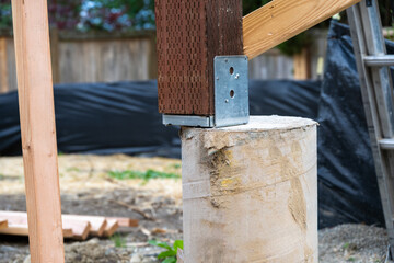 New house construction in residential neighborhood, closeup job site detail, round foundation cement pouring form with metal bracket and wood 4x4 beam installed  © knelson20