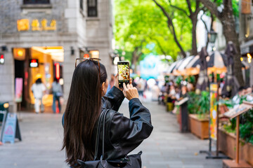 Young female tourist taking a photo of the Xintiandi shopping street landmark and popular...