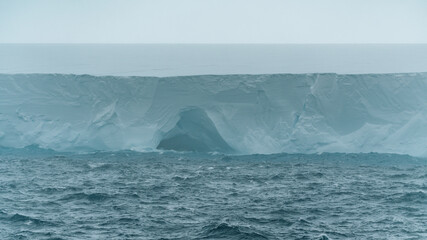 A23a Iceberg Antarctica Ice Cave Close Up Rough Seas Moody Clouds Fog and Dark Ocean. Ice Shelf Climate Change Scenic Cruise View