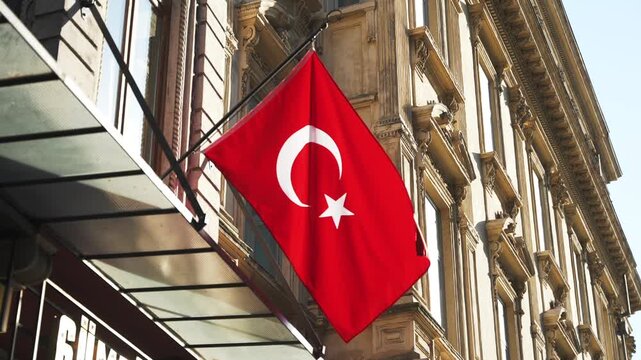 Close up of national Turkish flag waving in the wid on the old building wall illuminated by sunlight on the street in Istanbul