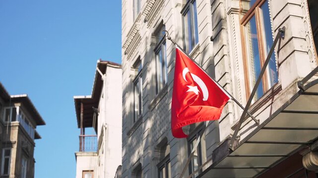Close up of national Turkish flag waving in the wid on the old building wall illuminated by sunlight on the street in Istanbul