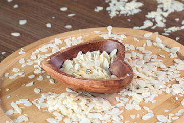 Flake sliced almonds in heart shaped wooden stand. Wooden dishes and healthy eating.