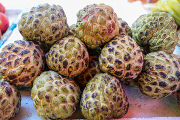 A close up image of ripe custard apples, highlighting their unique texture and color. Close Up of Custard Apples at local market stall background.