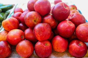 A close-up shot of a pile of fresh red apples in a market setting. The apples are ripe, glossy, and ready to be eaten. This image captures the beauty and freshness of this popular fruit.