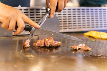 The chef is stirring the delicious Teppanyaki chicken and the aroma is overwhelming
