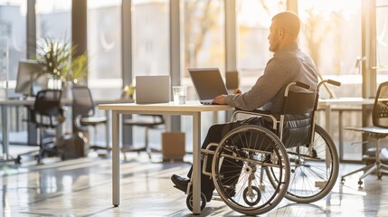 Man in wheelchair working on laptop in sunny office. Accessibility and inclusive work culture.