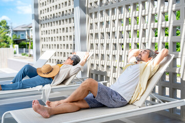 asian senior couple resting tranquility on beach chair at the swimming pool in the resort,elderly people lifestyle travel,relaxation