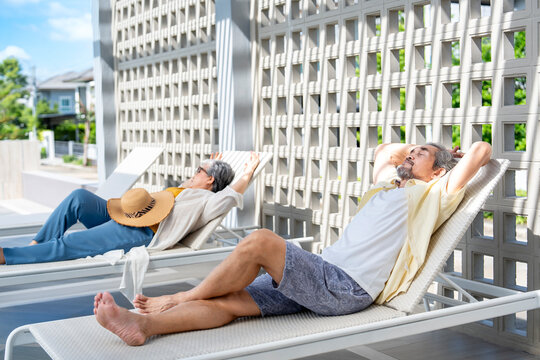 asian senior couple resting tranquility on beach chair at the swimming pool in the resort,elderly people lifestyle travel,relaxation