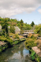 Fototapeta premium Old wooden bridge over a river with trees and reflections in a summer landscape