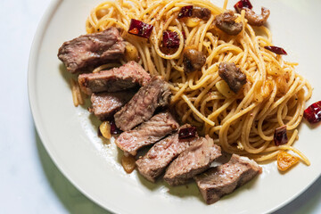 A delicious and tender steak, cooked to perfection, is served with a side of spaghetti pasta.