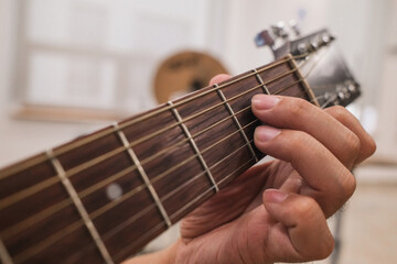 fingers on guitar strings, man learning to play acoustic guitar