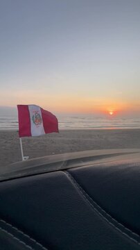 Bandera del Peru flameando frente al mar en el atardecer