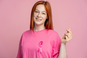 Woman showing korean symbol, k pop culture, wearing pink t shirt with pink ribbon breast cancer