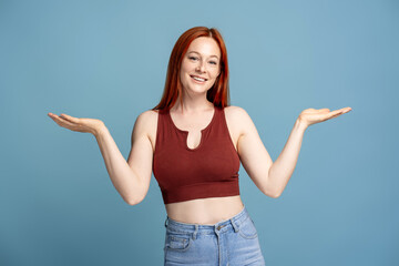 Naklejka premium Woman showing something on empty hands wearing casual clothes on blue background