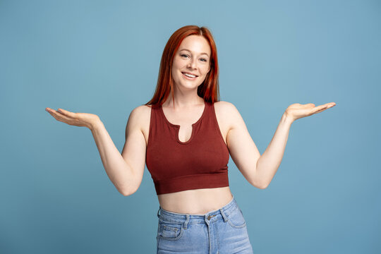 Woman showing something on empty hands wearing casual clothes on blue background