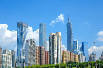 Naklejka premium Skyscrapers Reaching into a Bright Blue Sky with White Clouds on a Sunny Day