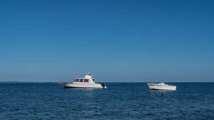 Boats in the ocean. A motorboat and a white yacht on the blue surface of the endless sea, against a clear sky. Ripples on the water. Madagascar.