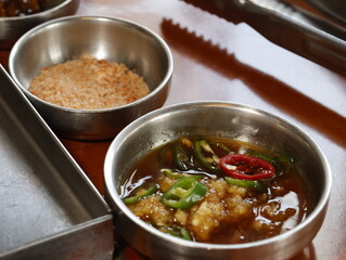 Korean bbq garlic dipping sauces in metal bowls on wooden table