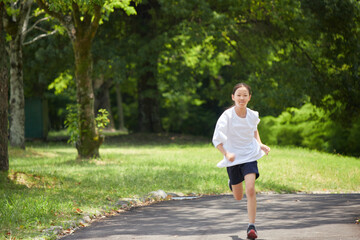 Fototapeta premium 夏休みの公園で楽しく遊んでいる小学生の女の子の様子