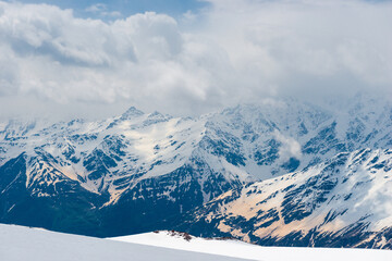 Obraz premium A picturesque view of the rocky white peaks of the mountains of the North Caucasus range from the snow-covered slope of Mount Elbrus. Caucasus