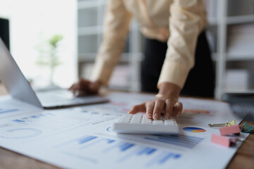 woman meticulously plans a finance audit, using a computer and calculator to review budget...
