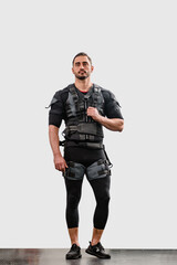 Strong young man dressed in black EMS suit during electric muscle stimulation workout, Workout efficiency: Isolated man using electro muscle stimulation, ideal for promoting effective training