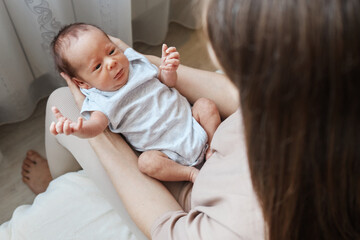 Anonymous brown haired mother embracing her newborn son tenderly holding her charming baby feeling happiness of motherhood enjoying the affectionate bond