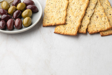 Close view of apile of whole grain crackers and a dish with olives with copy space