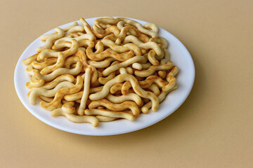 Crunchy organic mini crackers in a plate on a dark orange background