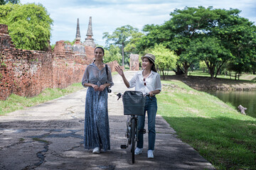 Obraz premium Woman travel in historical temple with bicycle. Tourist Travel taking a photo temple in Ayutthaya historical Park UNESCO world heritage site. 