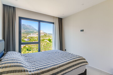 Angled shot of a master bedroom showing a king sized bed next to a large window