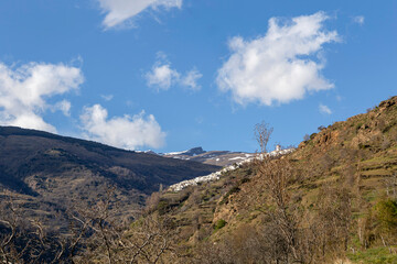 Distant view of the town of Capileira in Sierra Nevada and the Veleta peak, the fourth highest in Spain. Granada, Andalusia, Spain.