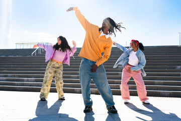 Young group of multiethnic hip-hop dancers wearing colorful urban streetwear dancing - Stylish multiracial rap crew portrait in the city