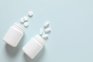 Various medicines and health pills poured from a medical white bottles, healthcare and medical on a colorful blue background.