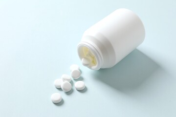 Various medicines and health pills poured from a medical white bottle, healthcare and medical top view on a color background.
