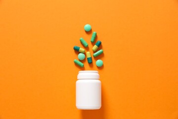 Various medicines and health pills poured from a medical white bottle, healthcare and medical top view on a color background.