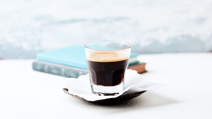 Coffee in glass cup on bright wooden background. Copy space.