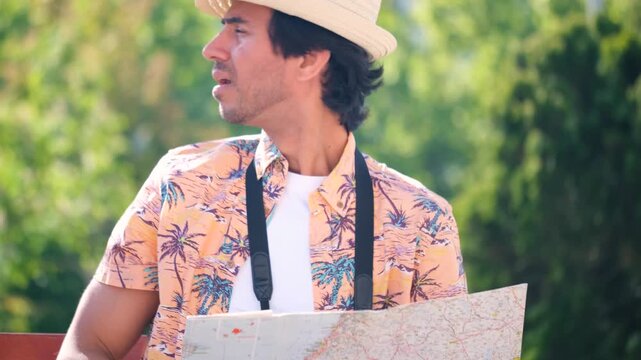Indian tourist man wearing a straw hat is looking at a map lost. He is confused