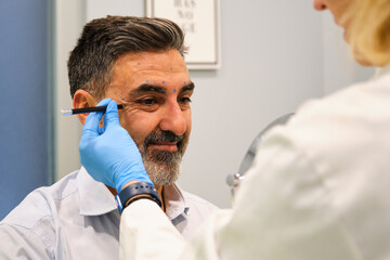 A man is getting ready to get Botox for crow's feet or laugh lines wrinkles by a aesthetic doctor...
