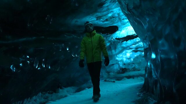 Male hiker walking in ice cave, Vatnajokull glacier, Hvannadalshnukur, Iceland next to Jokulsarlon