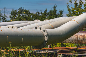 usty pipes, screws, rivets. industrial landscape against the background of blue sky and white clouds © Adam