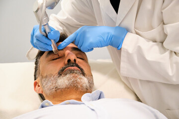 A man is getting a Non-Surgical Eyelid Lift or blepharoplasty, lifting laser eyelid.